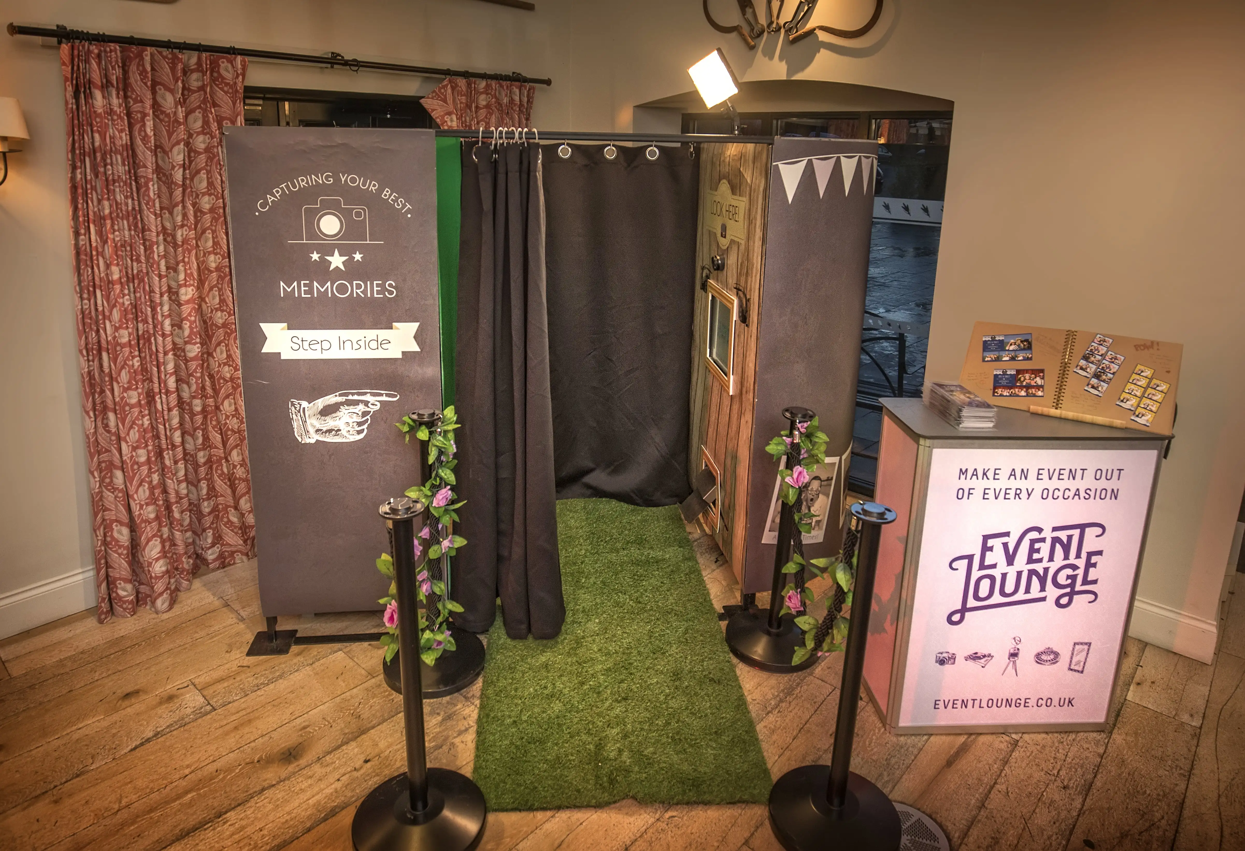 Indoor photo booth with black curtains, green carpet, and an Event Lounge sign promoting event photos.