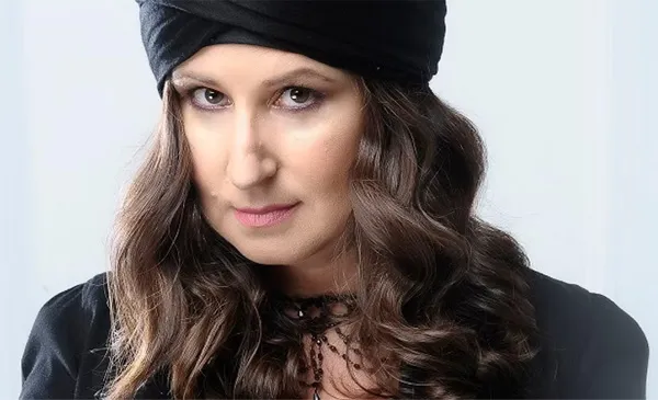 Amelie wearing a black headwrap and black top looking attentively at the camera.
