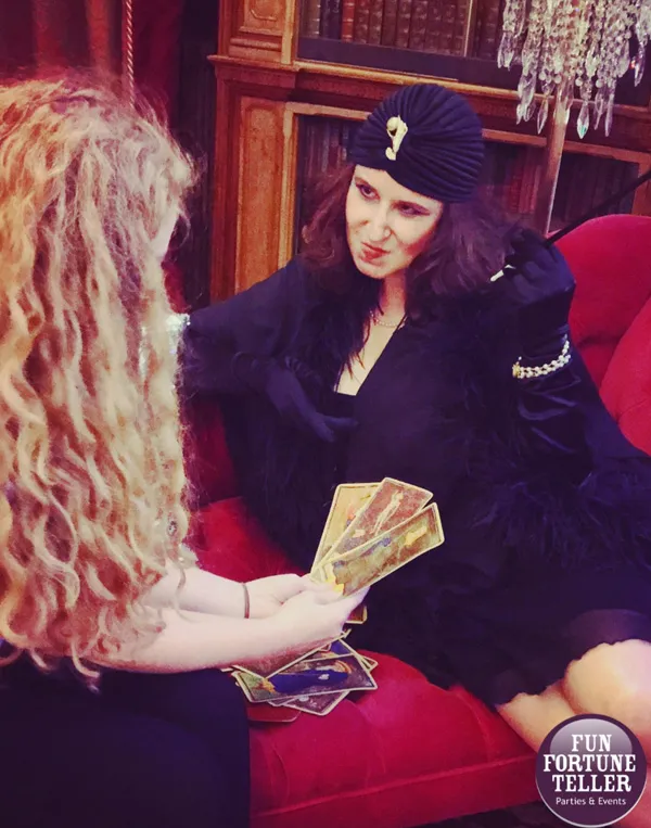 Amelie gives a tarot reading on a red couch.