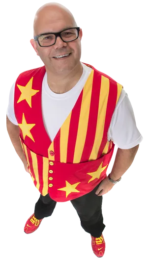 Smiling man with glasses wearing a red vest with yellow stars and stripes, white shirt, black trousers.