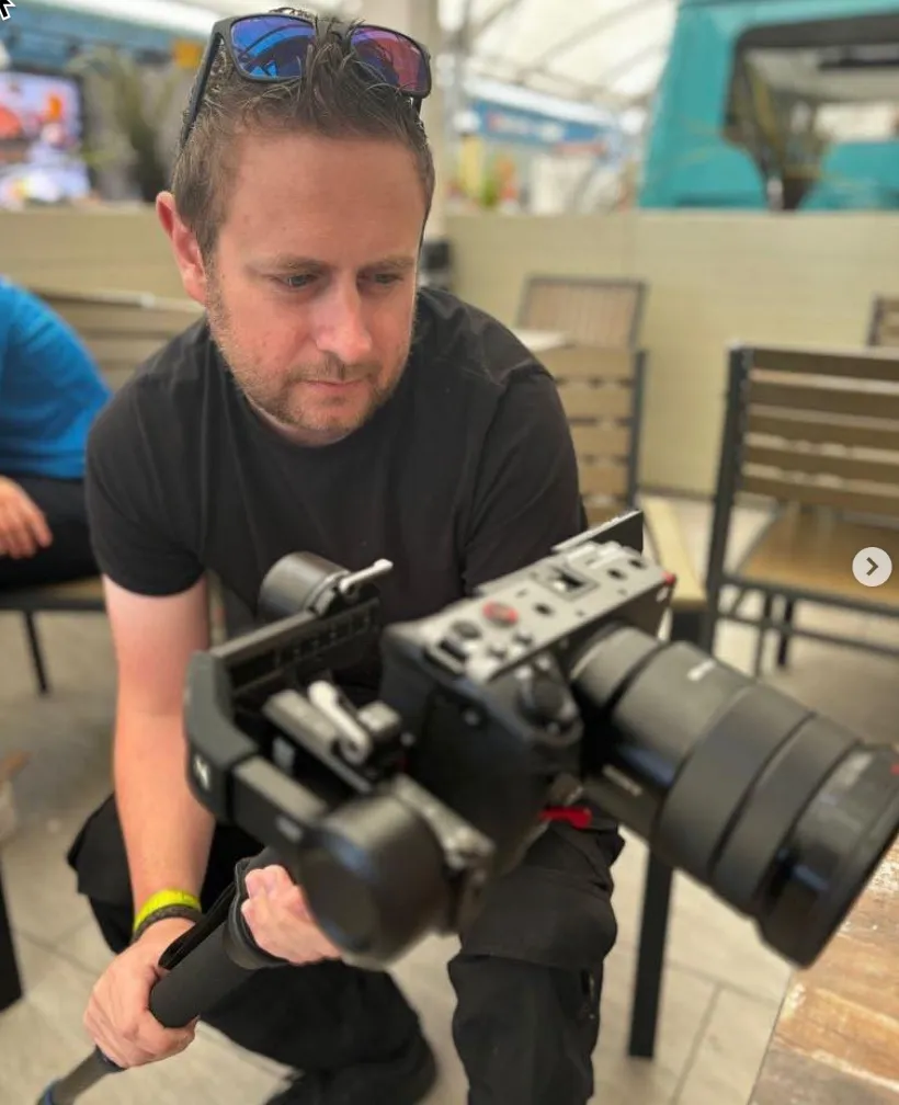Man in black shirt holding a professional camera with gimbal.
